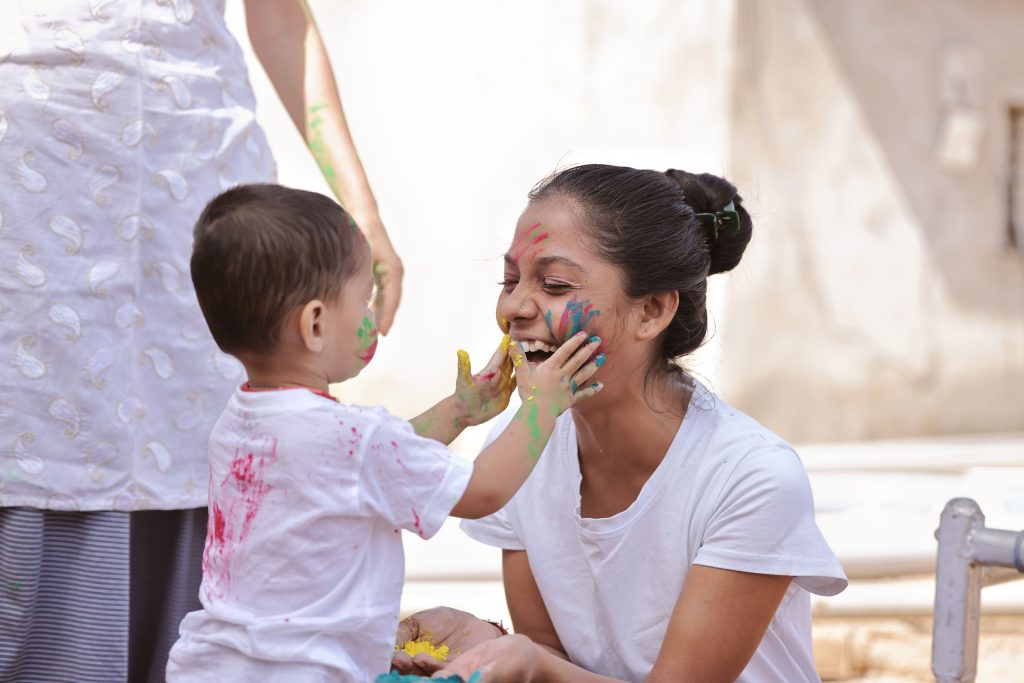 Joyful mother and child playing with vibrant face paint outdoors, capturing fun and bonding moments.